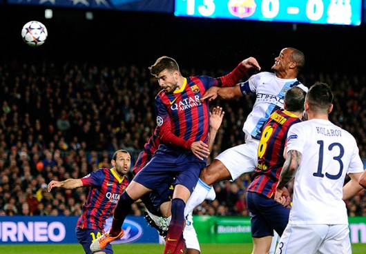 BARCELONA, SPAIN - MARCH 12: Gerard Pique of Barcelona and Vincent Kompany of Manchester City compete for a header during the UEFA Champions League Round of 16, second leg match between FC Barcelona and Manchester City at Camp Nou on March 12, 2014 in Barcelona, Spain. (Photo by David Ramos/Getty Images)